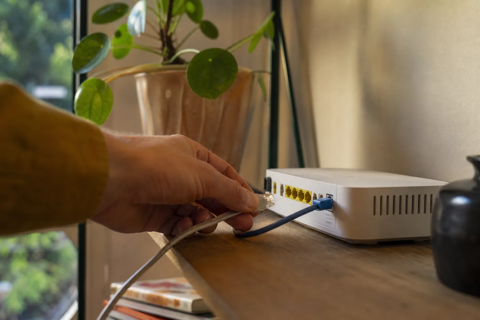 Thuiswerkplek met een wifi-router op de voorgrond waarvan de lampjes branden, op de achtergrond een laptop met een inlogscherm van een bankwebsite